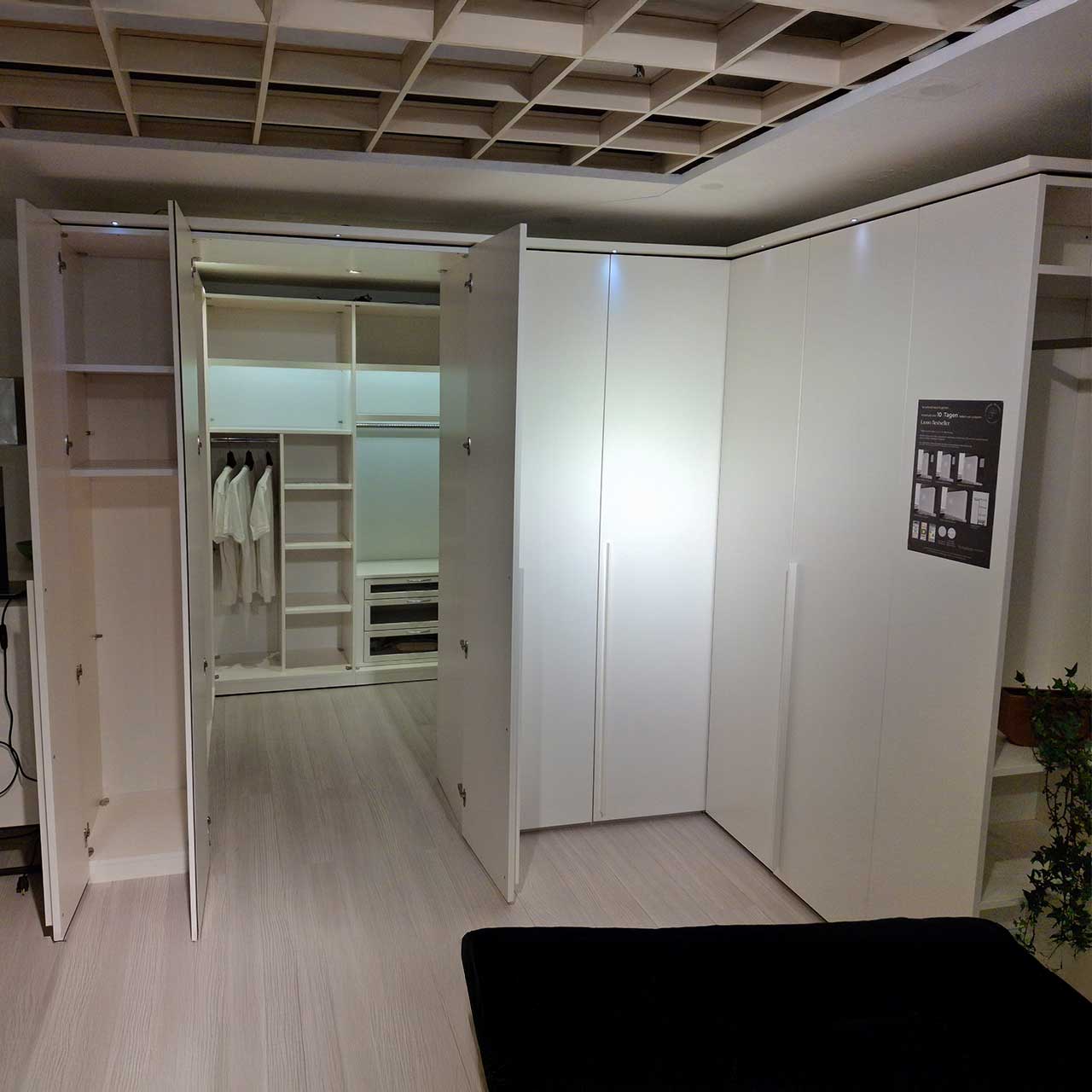 Loddenkemper begehbarer Kleiderschrank - Außenansicht mit geöffneter Tür Die linke geöffnete Tür gibt den Blick frei auf zwei Einlegeböden, die folgenden zwei Türen führen in den Kleiderschrank hinein.