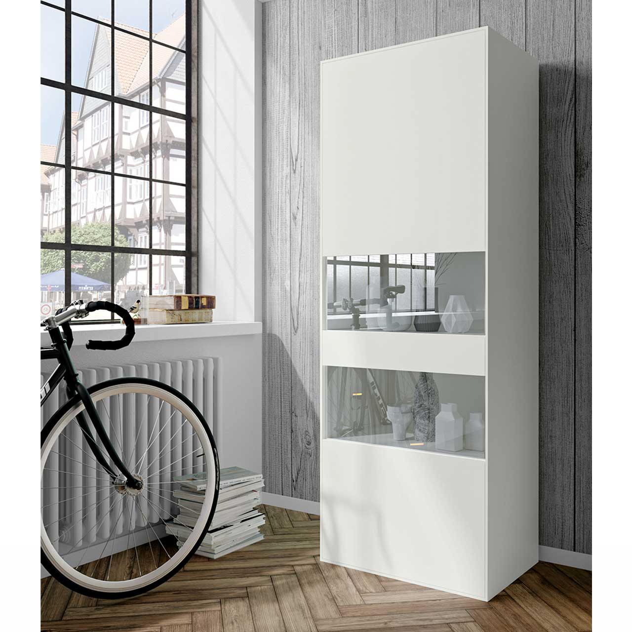 now! by hülsta - easy Vitrine 42113 / 42223 Milieubild: Weiße Vitrine mit zwei Glasausschnitten in der Tür im Wohnzimmer mit Dekoration.
