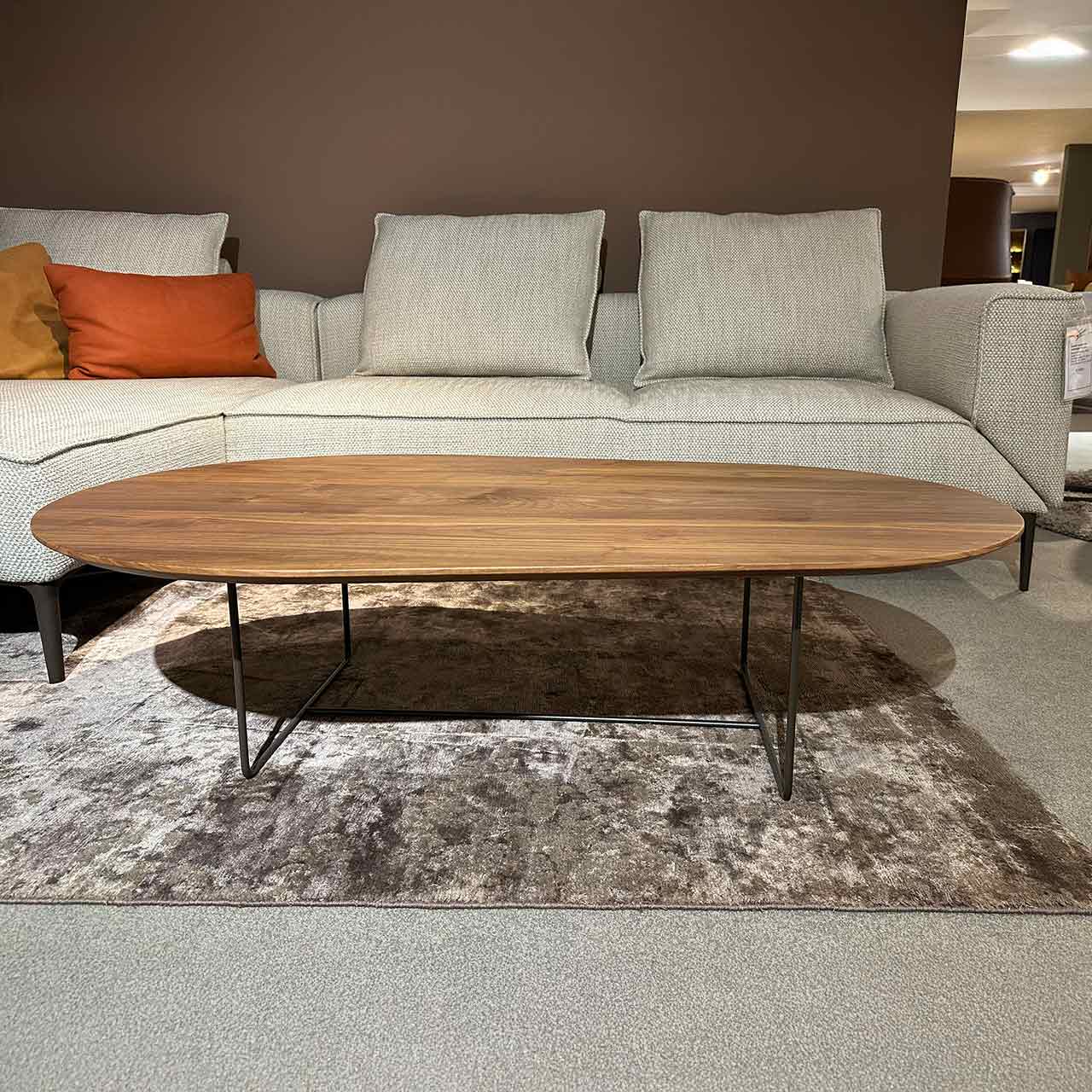 Ovaler Couchtisch mit Nussbaum-Tischplatte auf filigranem dunklem Gestell.