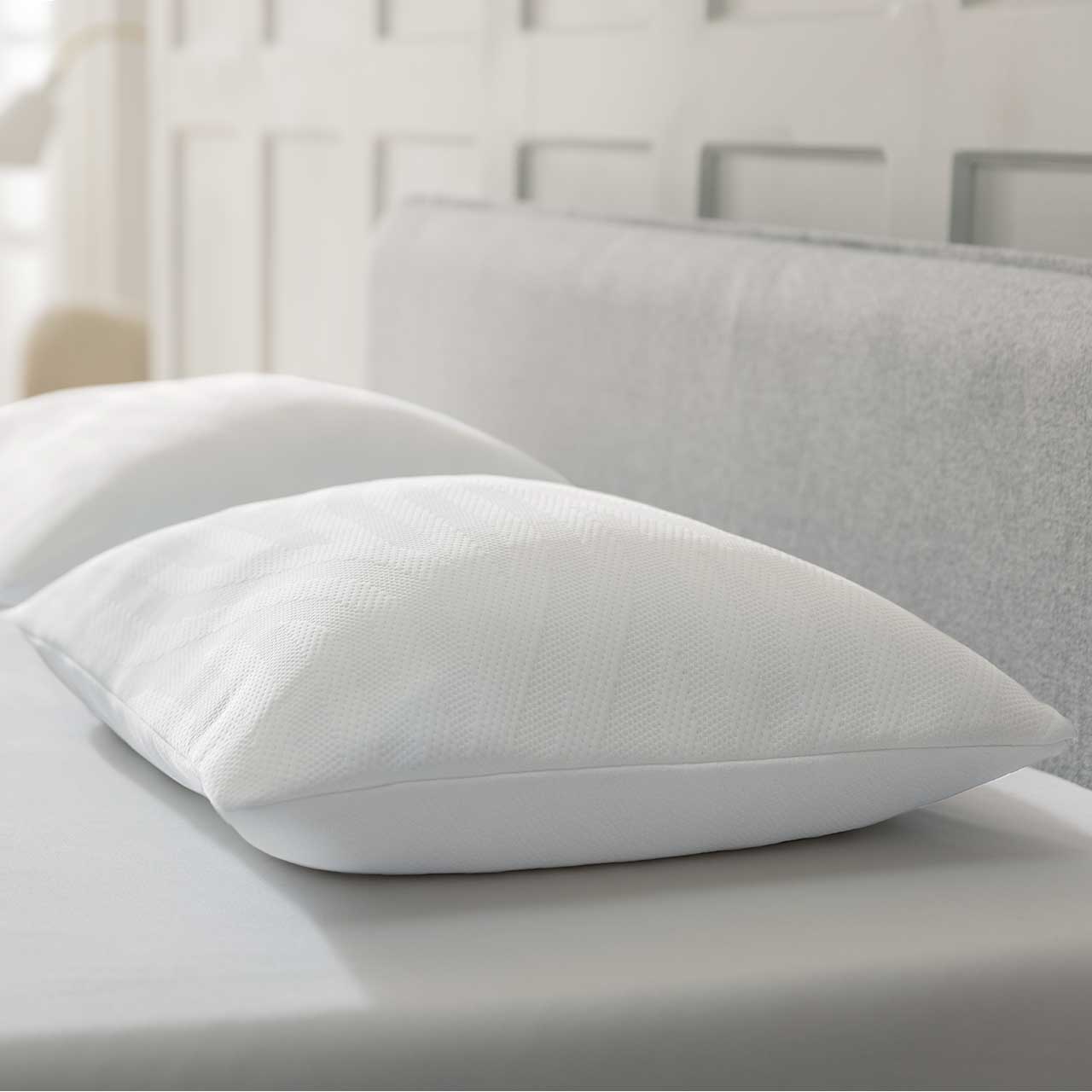 MH_Schlafzimmer_Kissen Produktbild Kissen in weiß auf einem hellgrauen Bett.