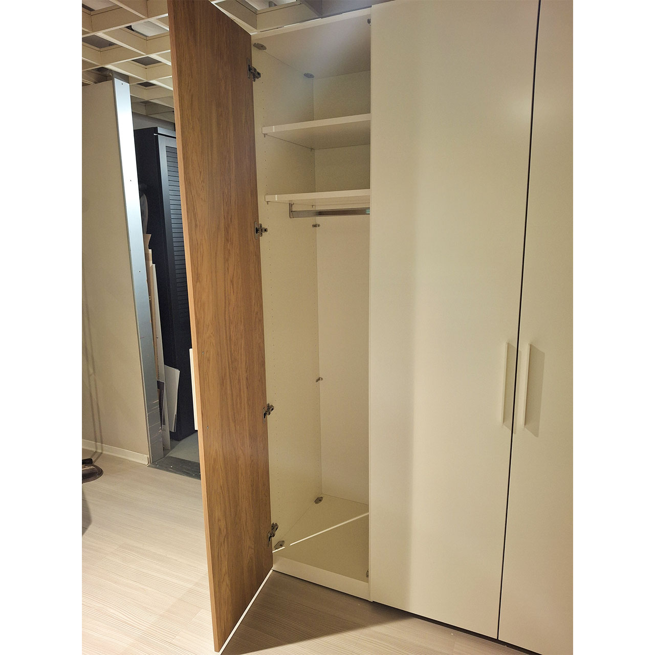 Detailaufnahme Kleiderschrank. Die linke Tür ist geöffnet. Zu sehen sind eine Kleiderschrank und zwei Einlegeböden.