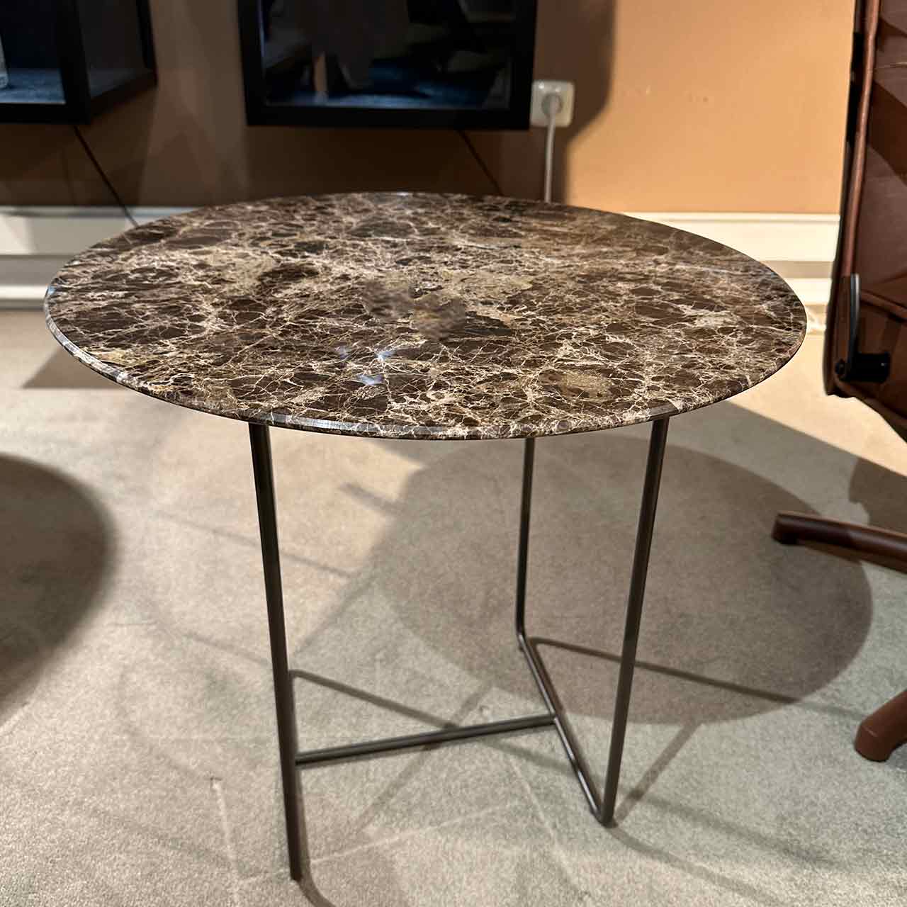 Couchtisch mit Marmor-Tischplatte auf filigranem dunklem Gestell.