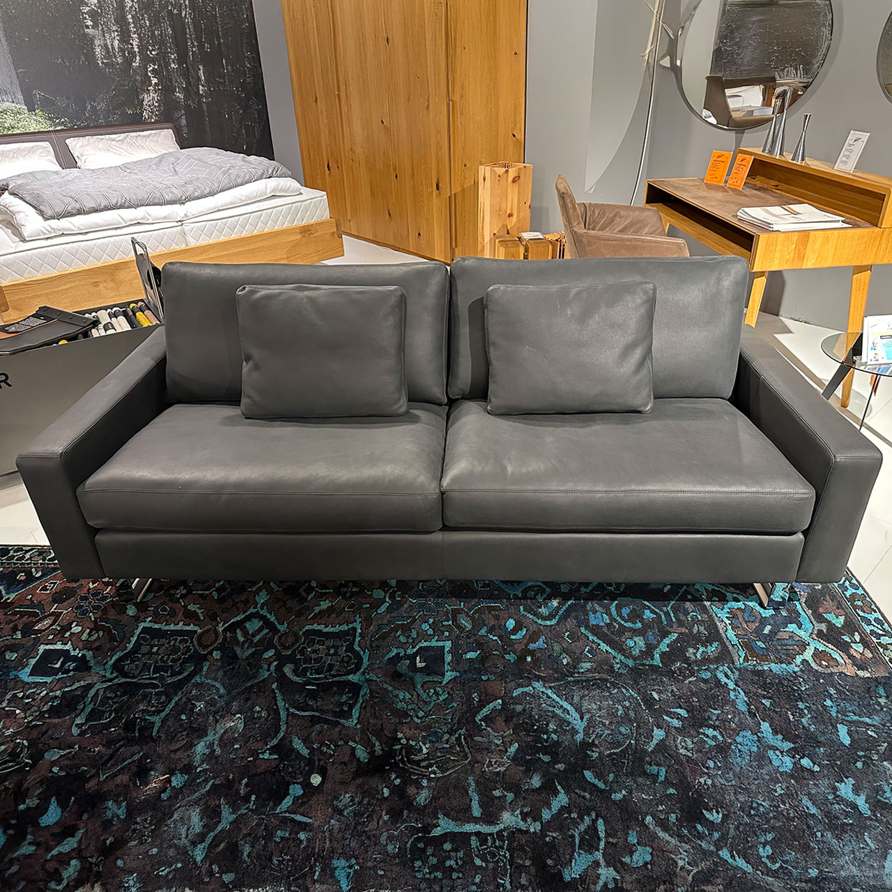 Zweisitzer-Sofa aus schwarzem Leder mit zwei passenden Kissen. Glänzende Kufen.