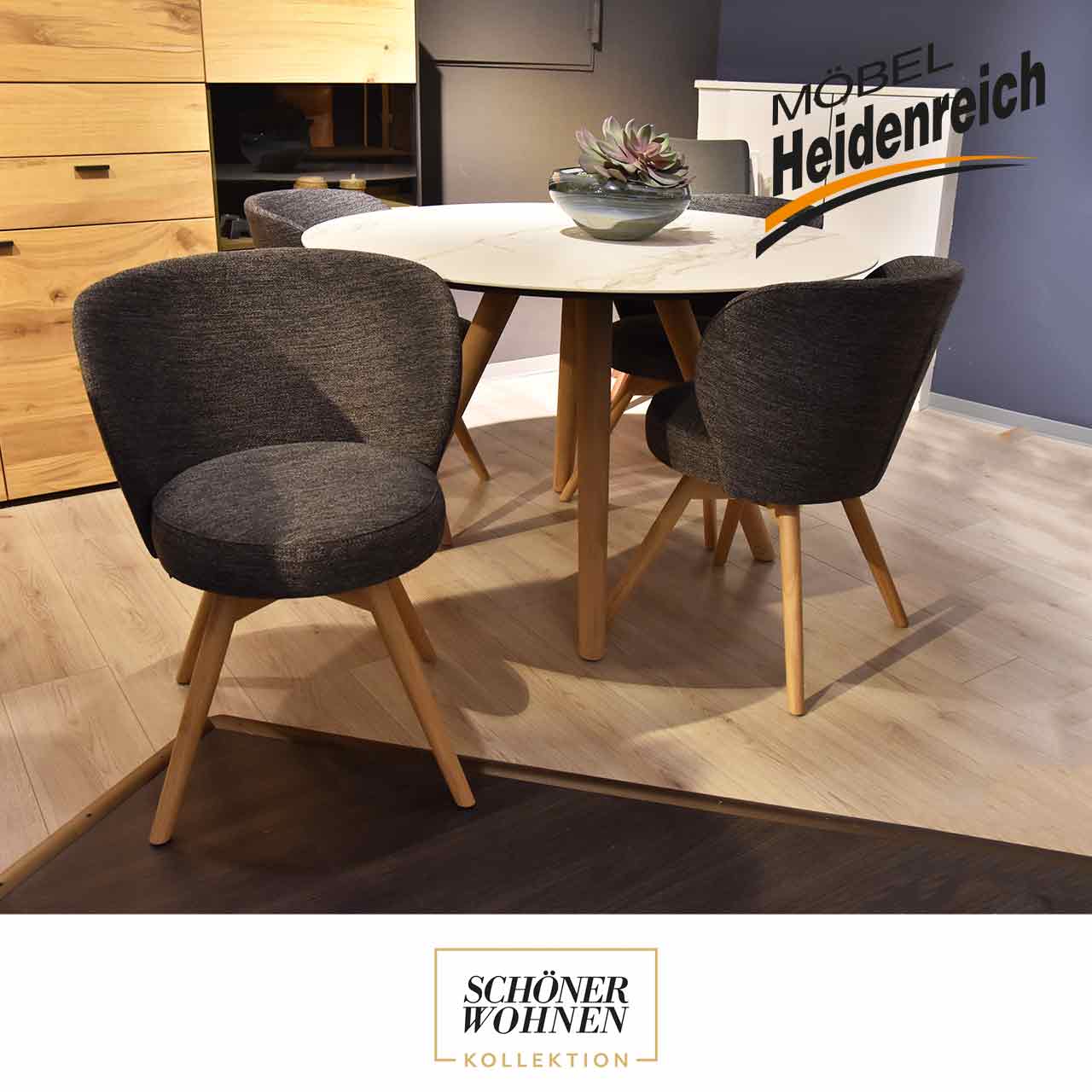 Schöner Wohnen - Stuhlset Turn Vier Stühle an einem runden Tisch. Ein Stuhl ist nach vorne gedreht. Die Stühle haben einen grauen Bezug und vier helle Holzbeine.