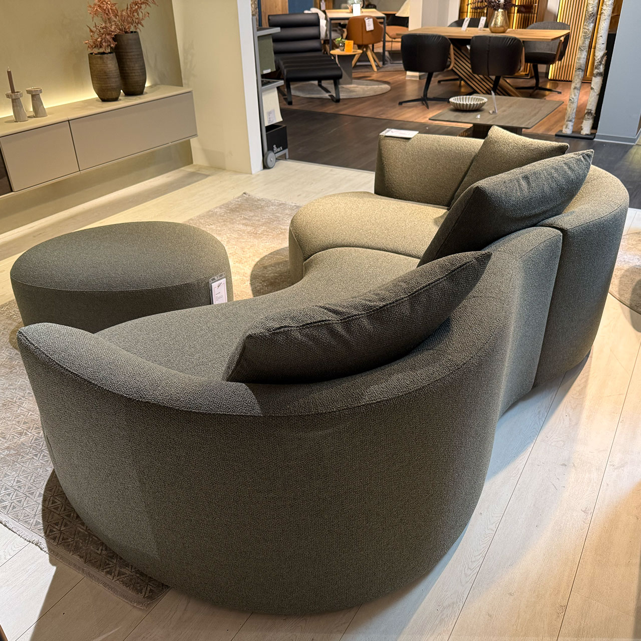 Organisch geformtes Sofa mit drei Kissen und organischem Hocker davor