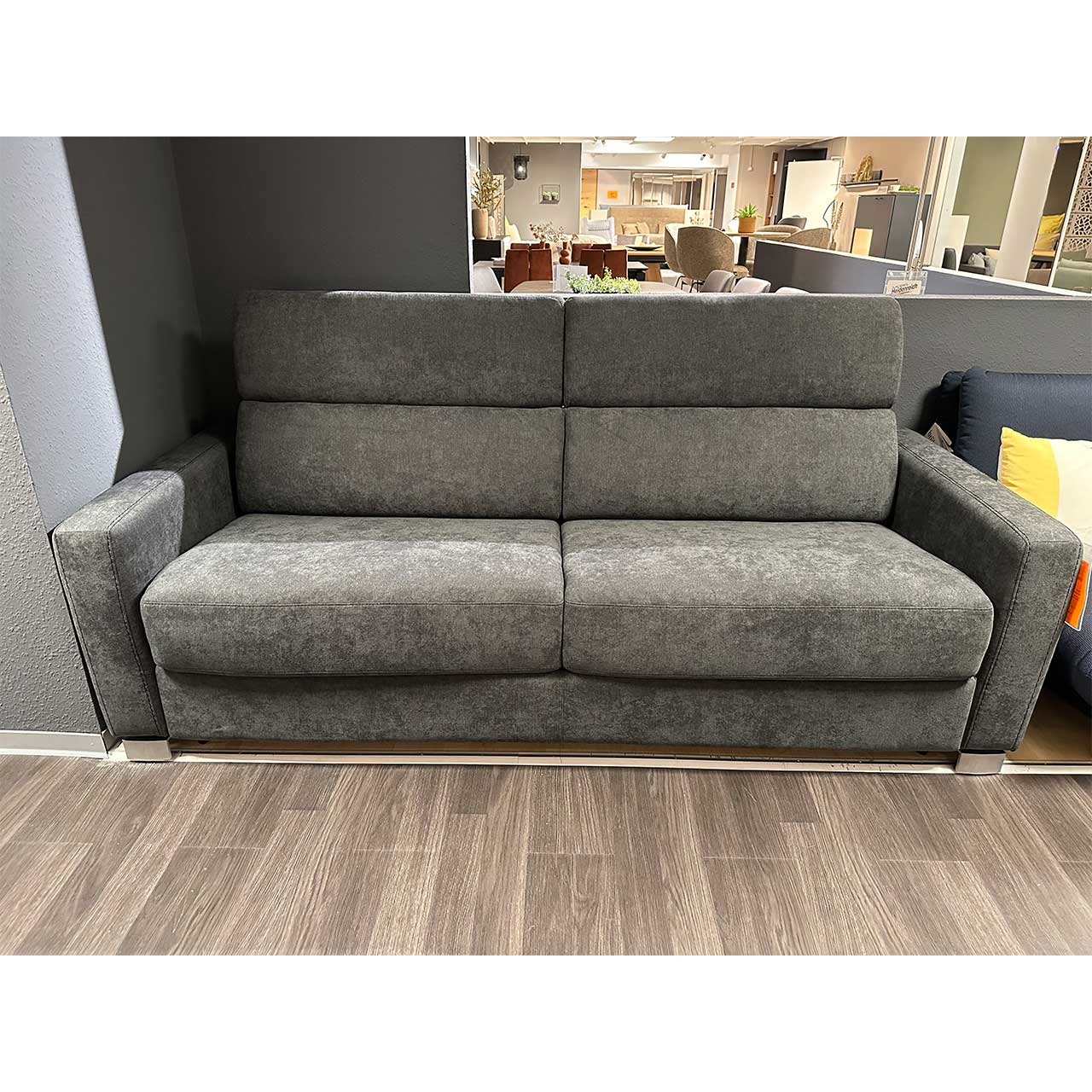 Graues stoffbezogenes Zweisitzer-Sofa mit hochgestellten Kopfstützen.