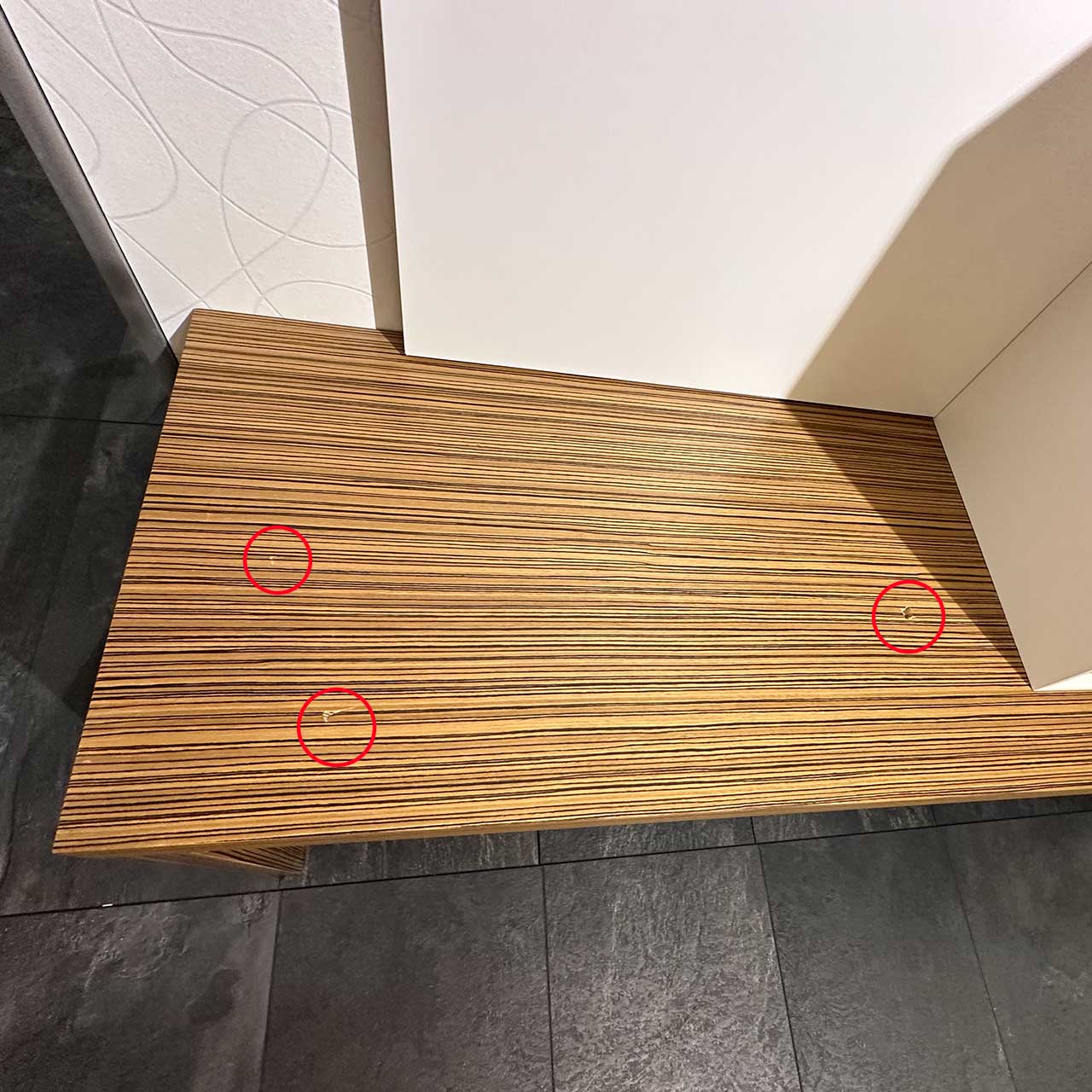 Auf der Fläche der Ablage sind drei kleine „Macken“, die mit roten Kreisen auf dem Bild gekennzeichnet sind. Aus der Ferne sind sie kaum sichtbar.
