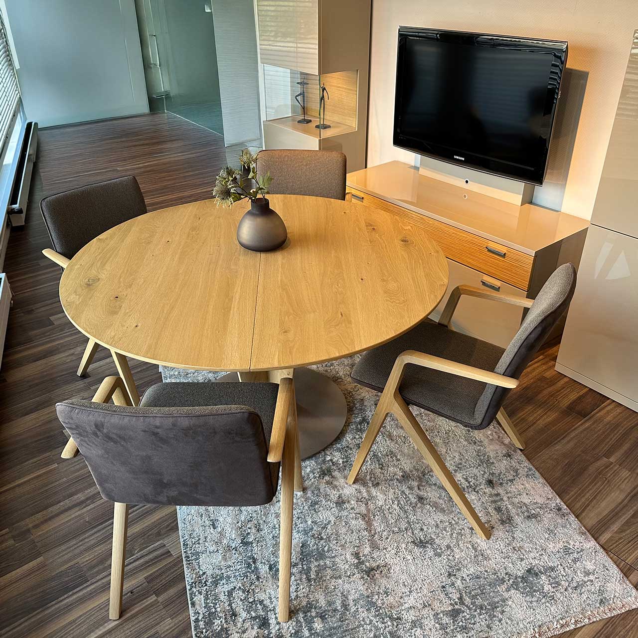 Runder Tisch aus hellem gemaserten Holz mit vier Stühlen im Möbelhaus fotografiert.
