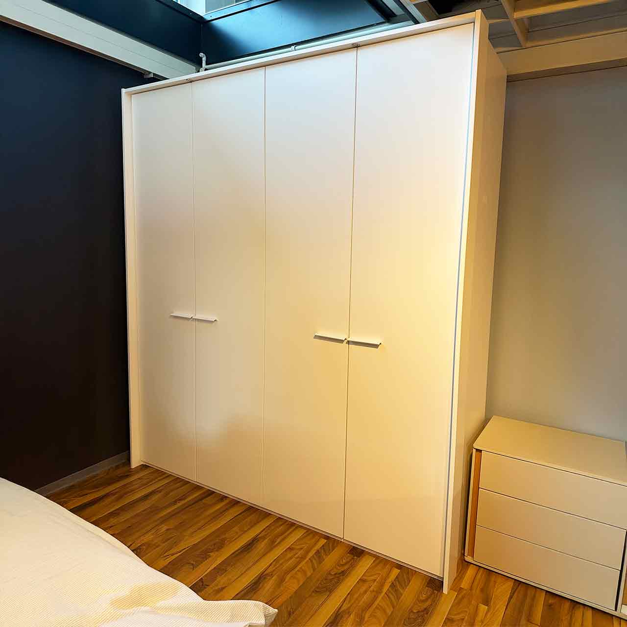 Weißer Kleiderschrank mit vier Türen und umlaufendem Passepartout.