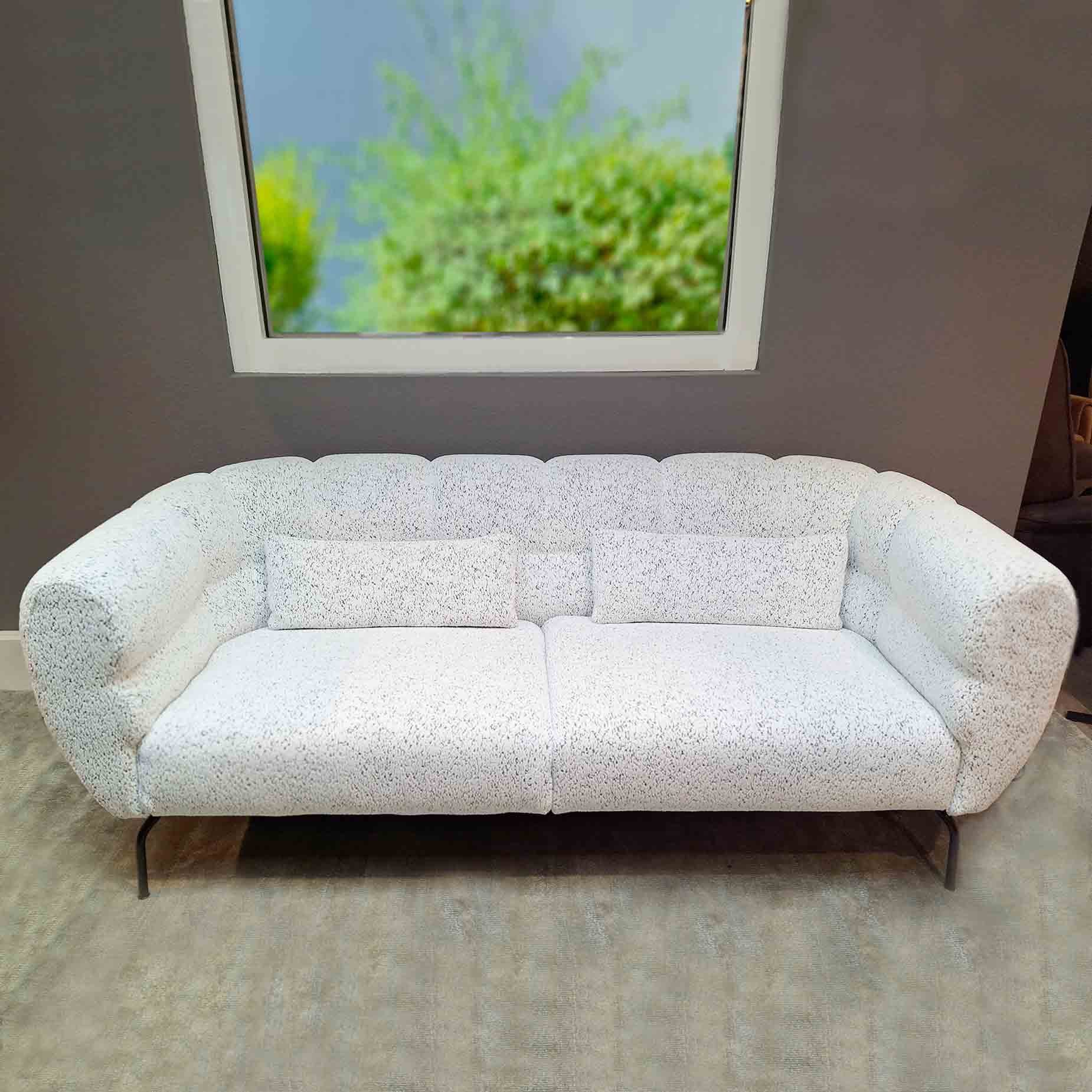 Sofa mit umschließender Armlehne in weiß-schwarz meliertem Stoff.