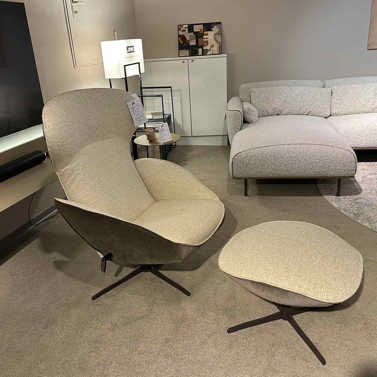 Sessel mit Hocker davor, beide mit Sternfuß. Sessel und Hocker zweifarbig: innen heller kuschliger Stoff, außen dunkler samtiger Stoff.