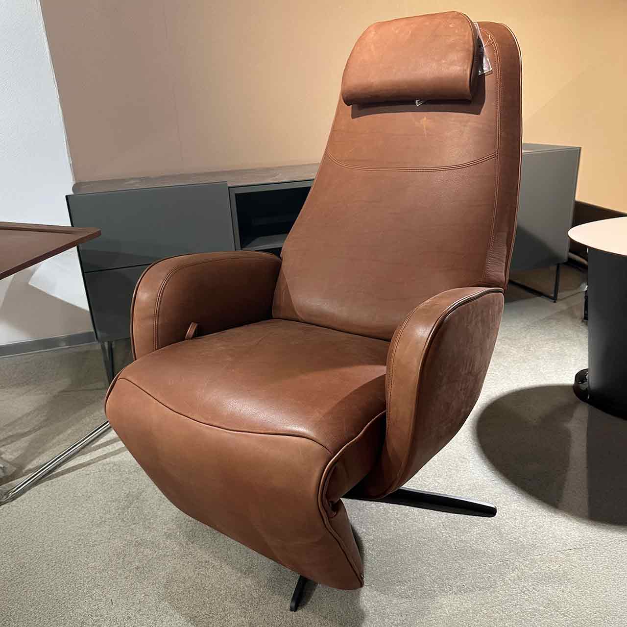 Dunkelbrauner Fernsehsessel mit sternförmigem Fuß und Kopfkissen oben an der Rückenlehne.