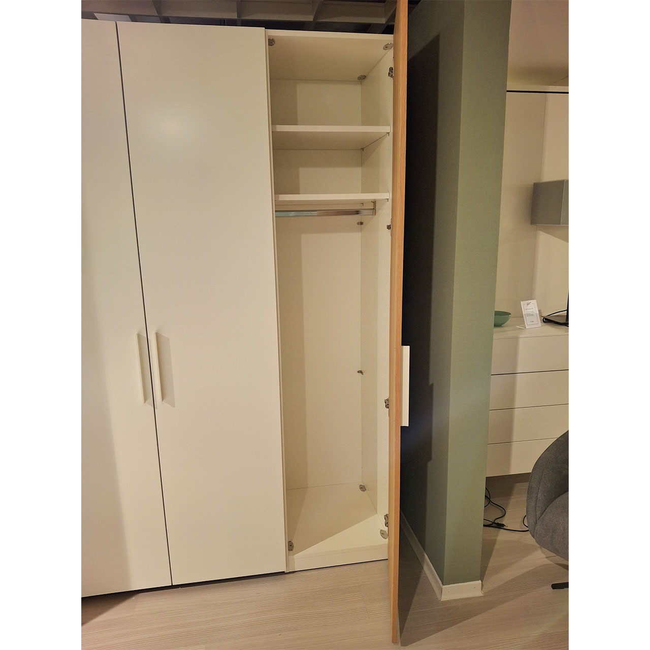 Detailaufnahme Kleiderschrank. Die rechte Tür ist geöffnet. Zu sehen sind eine Kleiderschrank und zwei Einlegeböden.