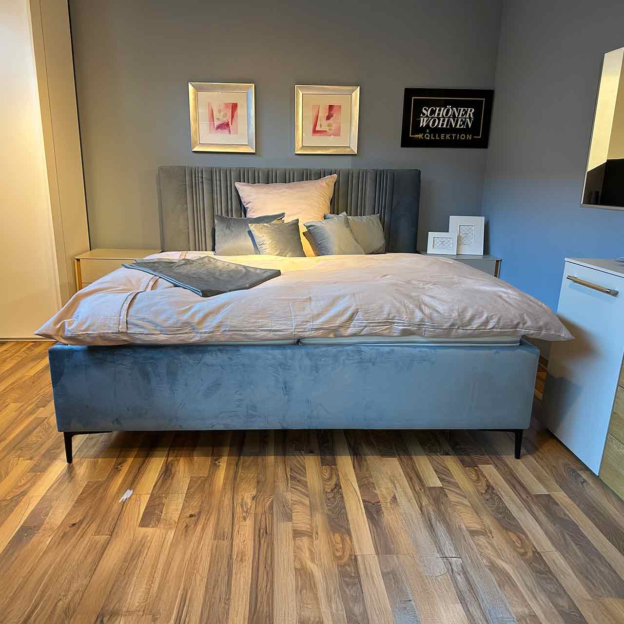 Bett mit hohem Kopfteil und schwarzen zierlichen Füßen aus Velourstoff in Blau-grau.