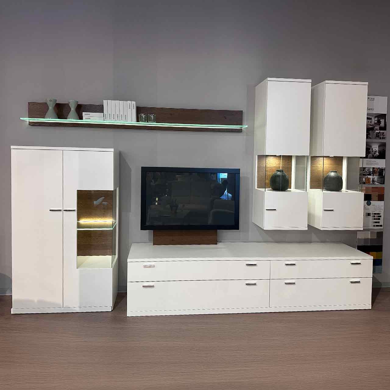 Links Highboard mit Vitrinen-Ausschnitt, daneben breites Lowboard, darüber hängen zwei schmale Vitrinenschränke und ein Wandbord